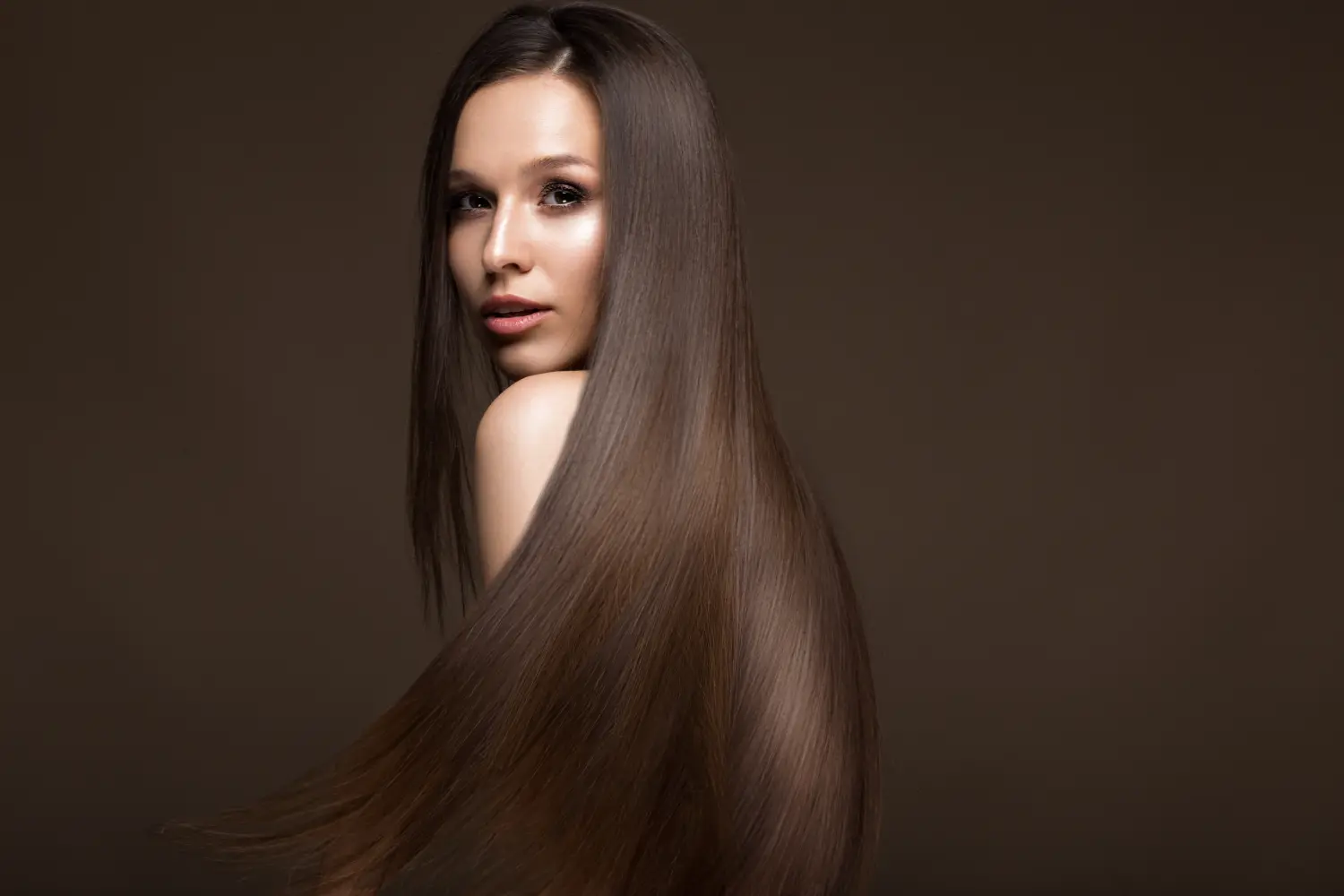 Schönes brünettes Mädchen in Bewegung mit perfekt glattem Haar und klassischem Make-up. Schönheitsgesicht. Bild aufgenommen im Studio.